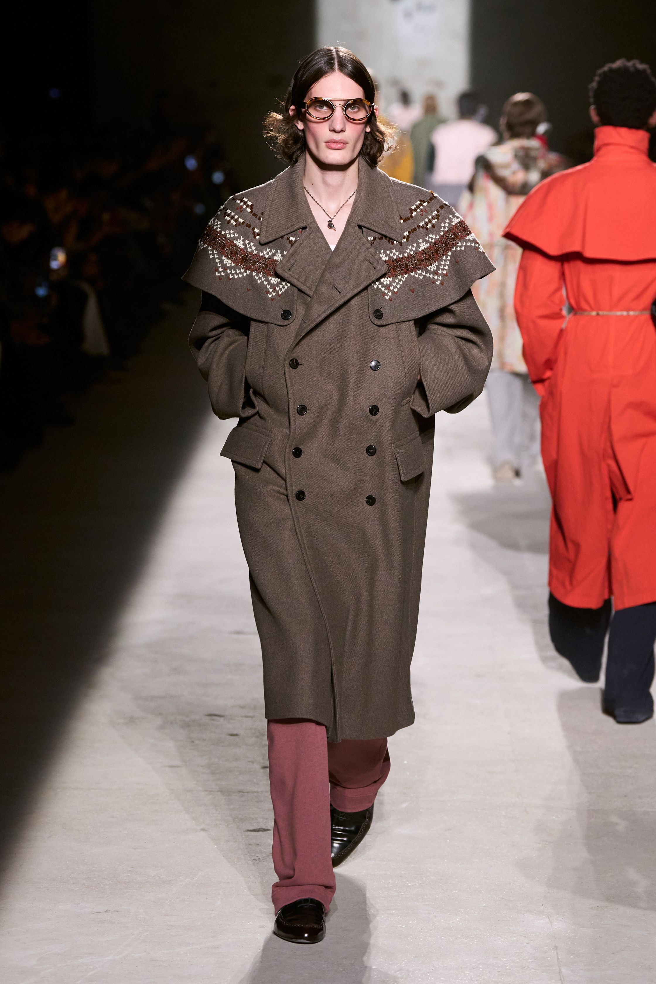 Dries Van Noten 2026秋冬以高度成熟的综合色彩与织物语言，继续书写其标志性的“文化层叠美学”。民族图案针织、拼接围巾、军装轮廓与优雅大衣在行走中形成复杂而克制的视觉节奏，色彩看似丰富却始终维持理性秩序。这是一种属于思想型穿着者的浪漫，不依赖情绪爆发，而通过织物、比例与色块的精密组合，构建出安静却极具深度的男性诗意-顽石频道趋势研究